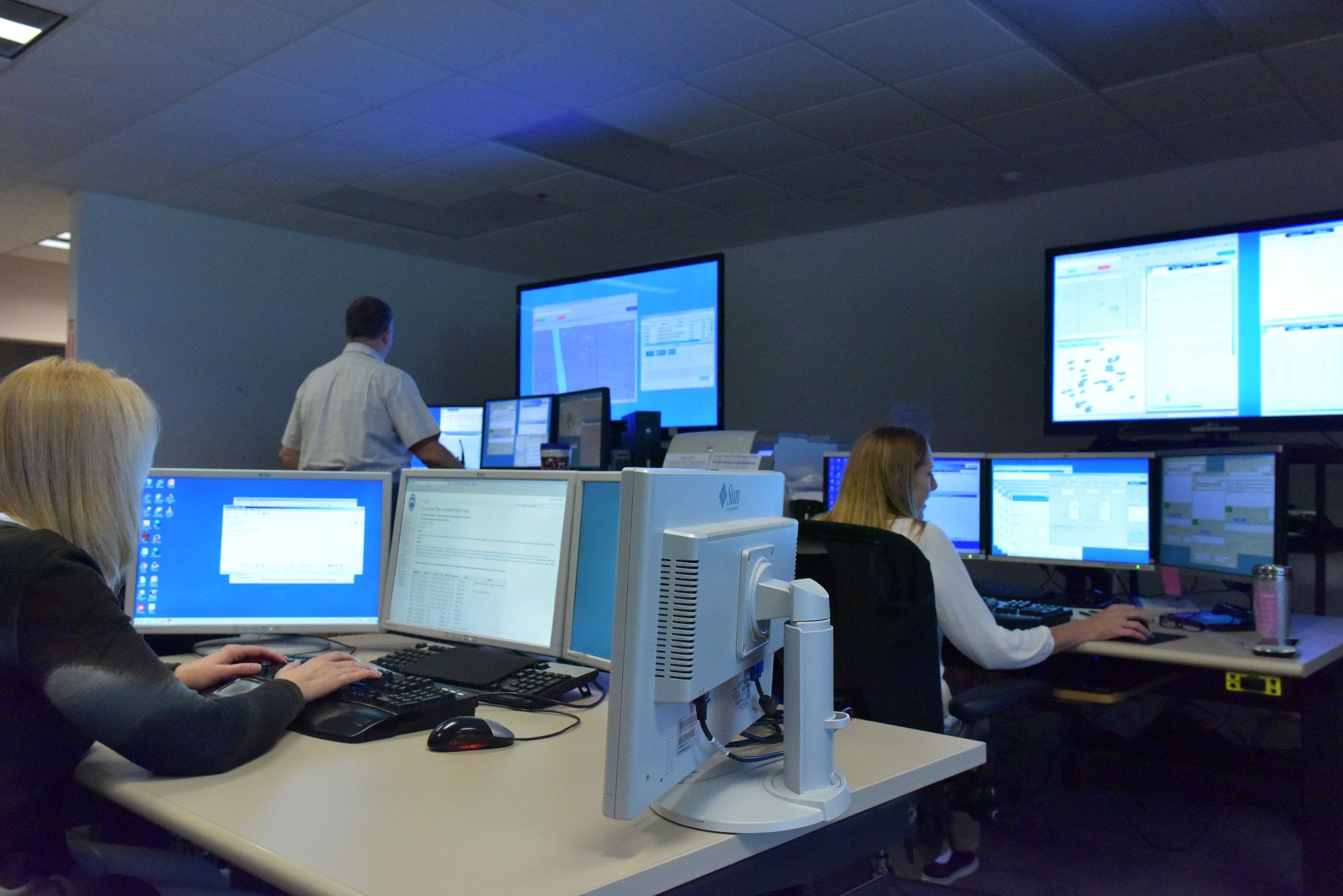 Tucson Police staff sit at work stations, each with multiple computer monitors.