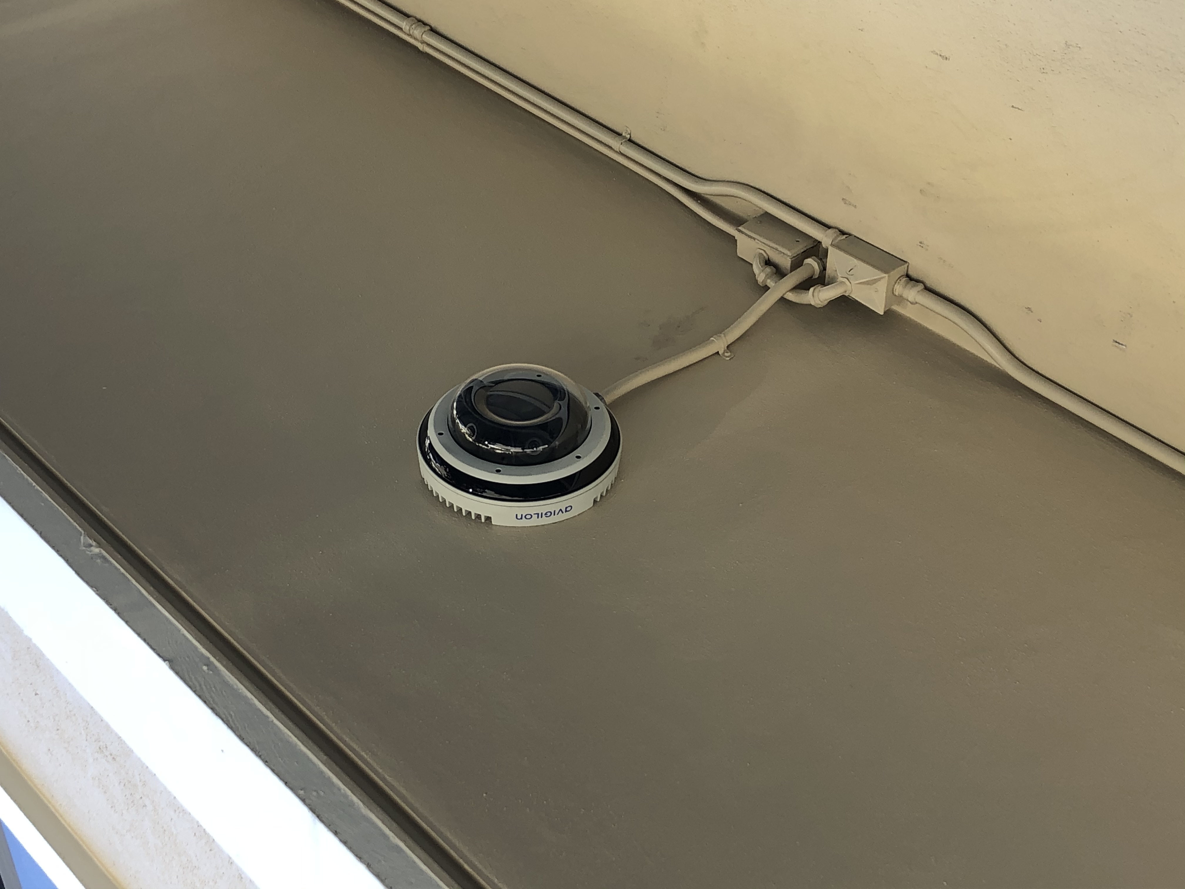 A saucer-shaped camera attached to the outside of the building.