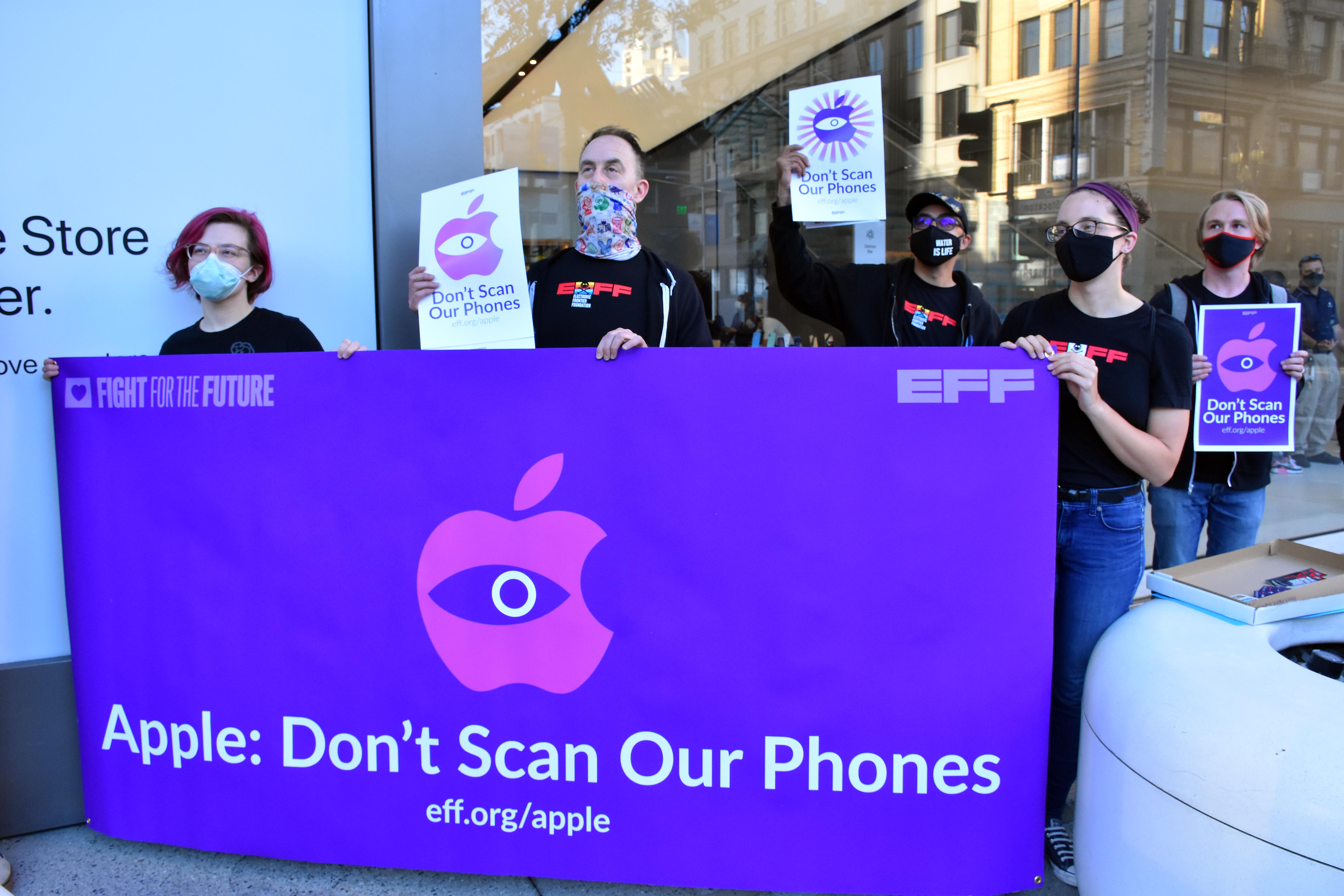 several people hold a banner that reads apple don't scan our phones in front of the apple store in san francisco