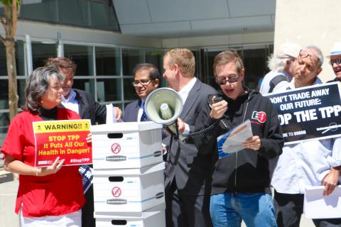 Jeremy Malcolm speaking into a microphone at a street rally