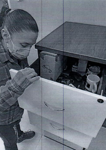 A black and white image of a woman looking in a filing cabinet. 